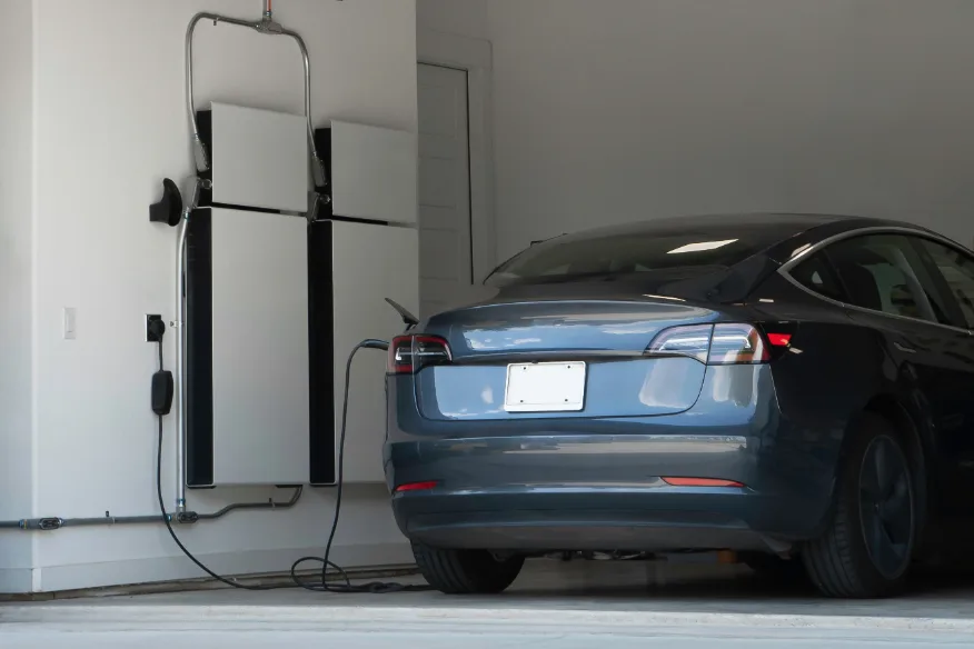 Electric car charging in a garage beside a home battery
