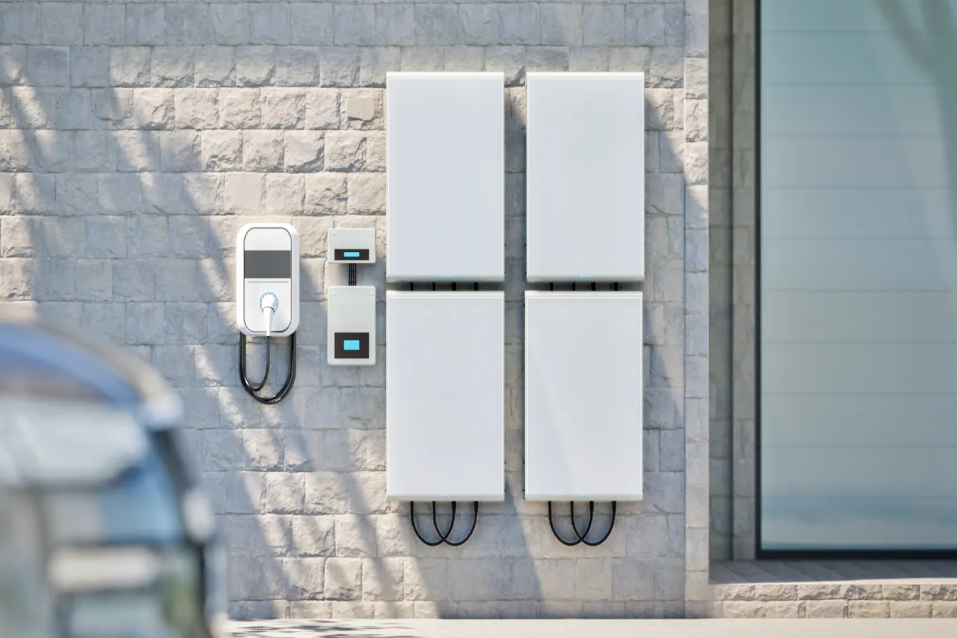 Wall-mounted home battery storage units beside a garage