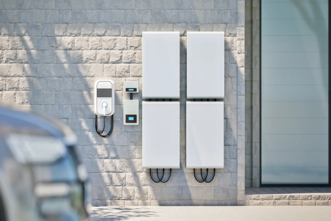 Wall-mounted home battery storage units beside a garage
